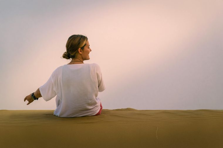 A woman seated in warm morning light, seen from behind, a moment of quiet